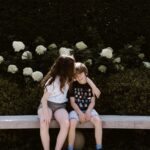 two toddler girl and boy sitting on concrete bench near outdoor during daytime
